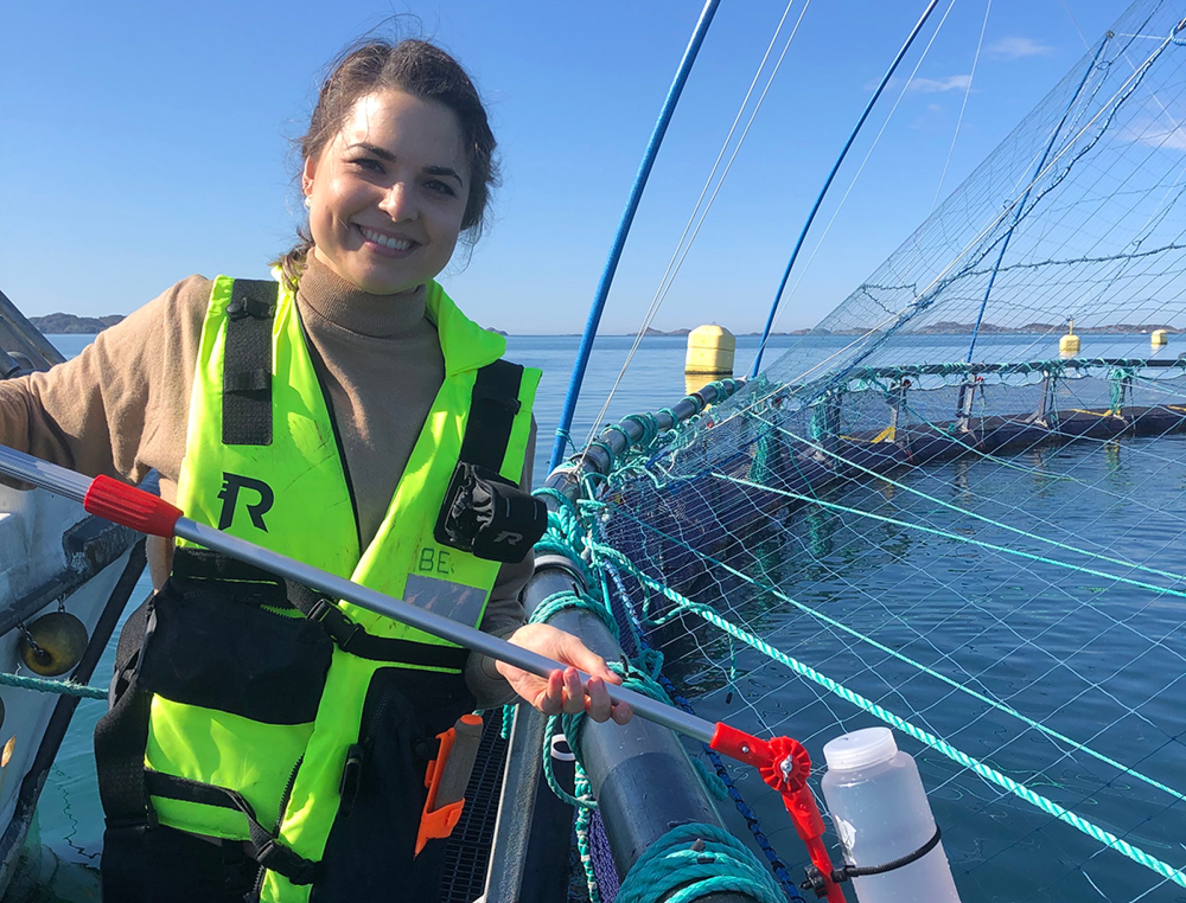 Lisa-Victoria Bernhardt demonstrates a 1 L water bottle attached to a telescopic swing sampler that was used to collect the water samples from the top layer within each net-pen. This approach was used during the more comprehensive field study, which demonstrated earlier SAV detection in the water samples compared to the fish samples collected in connection with the surveillance program for SAV/PD. Photo: Private.