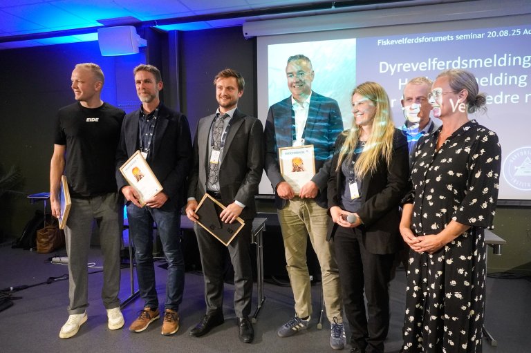 Fiskevelferdsprisen 2025 ble delt mellom AkvaFuture og Cermaq, Eide Fjordbruk og Salmar for å ha slutta med rensefisk. Her er vinnerne fra venstre: Sondre Eide fra Eide Fjordbruk, Anders Fjellheim fra Salmar, Thomas Myrholt fra AkvaFuture og Snorre Jonassen fra Cermaq. Ved siden av ham er Stine Gismervik fra Veterinærinstituttet, Pål Mugaas Jensen fra OceanSpace Media (Kyst.no) og Solveig Holm fra NCE Seafood Innovation. Foto Ole Andreas Drønen