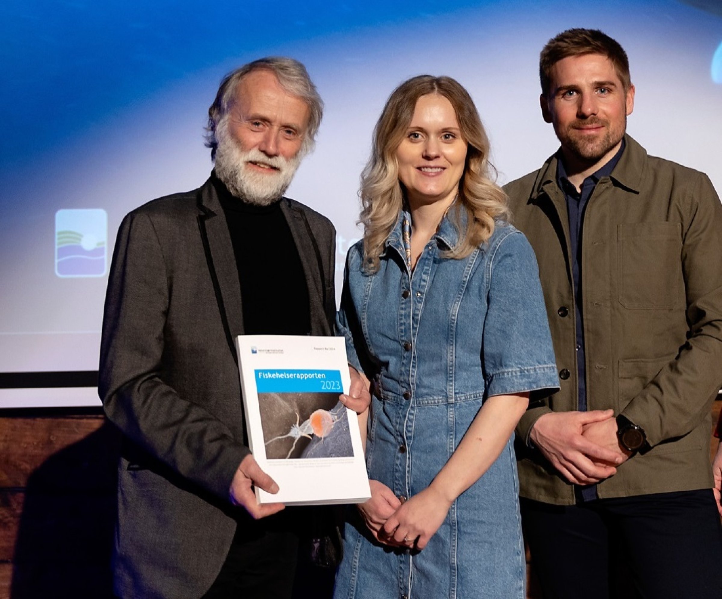 Edgar Brun til venstre, Hanna Sæteraas Bjerke i midten og Mattias B Lind til høyre står sammen med Fiskehelserapporten 2023 foran seg