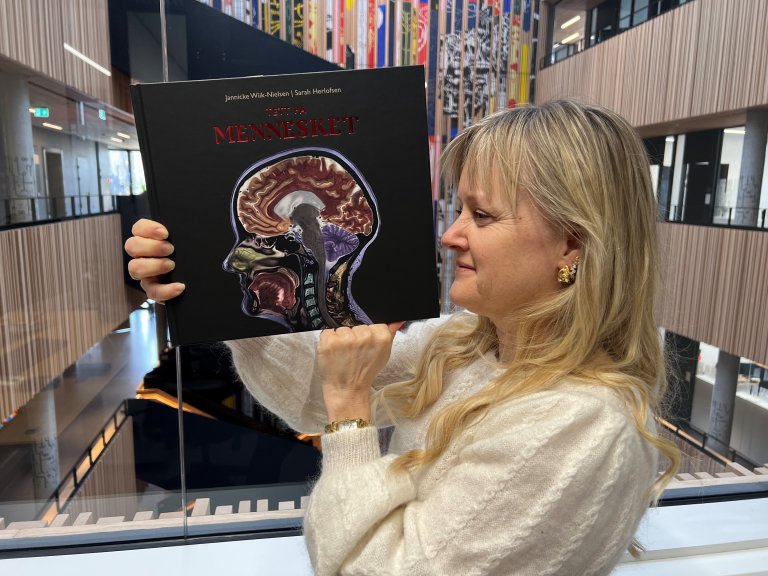 Forfatteren med sin nye bok med bilde av sitt eget hode tatt i elektronmikroskop. Foto: Bryndis Holm, Veterinærinstituttet