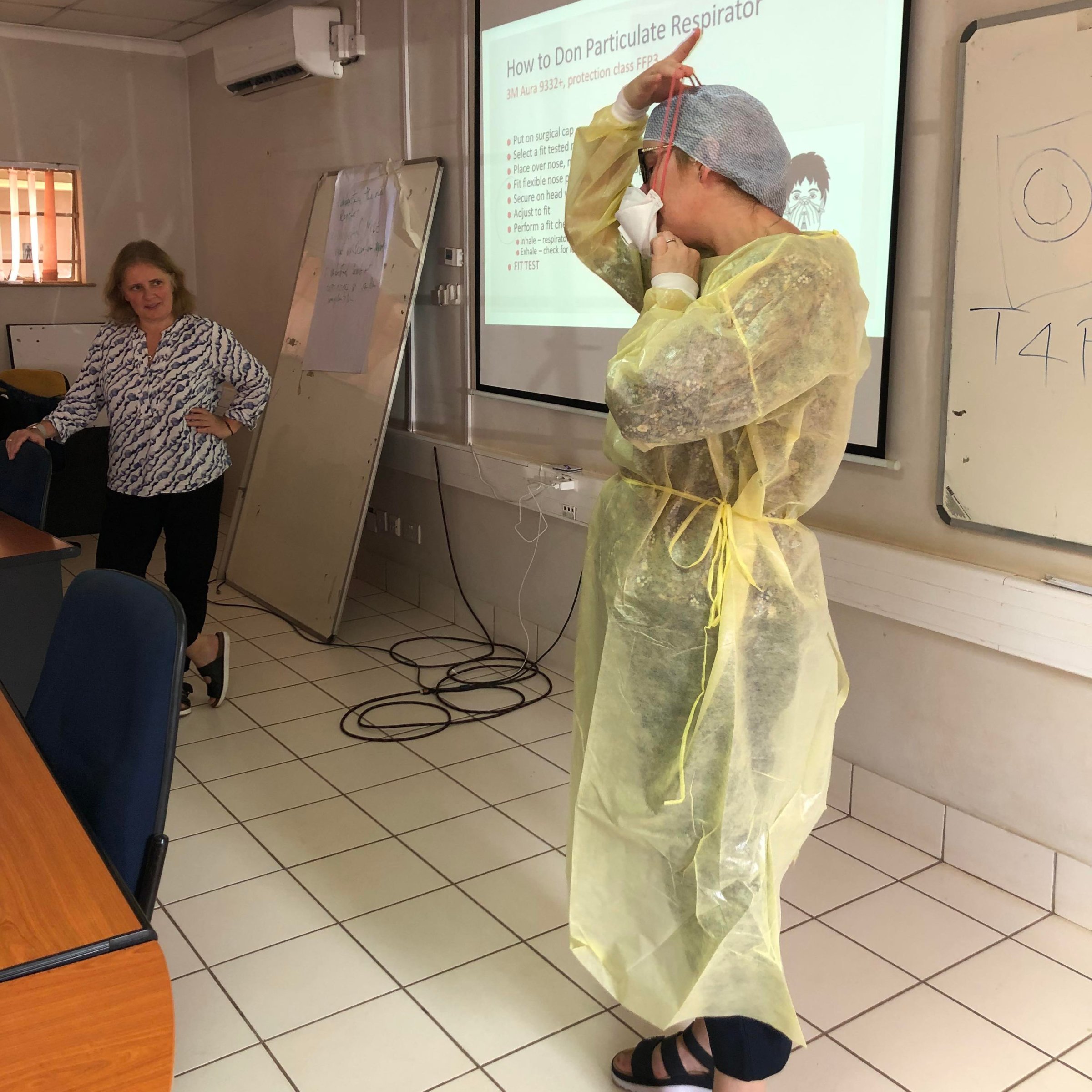 Tone Bjordal Johansen fra FHI illustrer riktig påkledning og avkledning av beskyttelsesutstyr ved håndtering av farlige smittestoffer. Foto: Siv Klevar